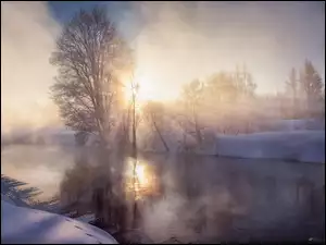 Zimowy wschód słońca nad zamgloną rzeką
