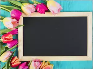 Kolorowe tulipany ułożone wokół czarnej tablicy