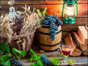 Kiście winogron na beczce obok słoja z winem w koszyku