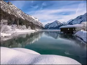Drewniana chata nad zimowym górskim jeziorem