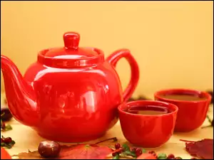 Dwie filiżanki herbaty obok czajniczka pośród liści i kasztanów