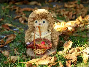 Ozdobna figurka jeża z koszem do liści jesienią