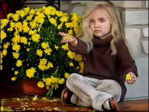 Dziewczynka siedząca pod ścianą i skubiąca kwiatki