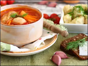 Zupa z warzywami i mięsem obok ciemnego chleba i ugotowanych ziemniaków