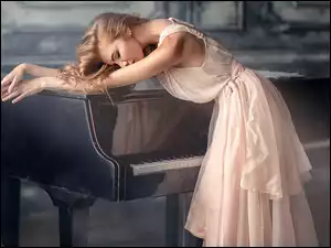 Kobieta w sukience oparta o fortepian