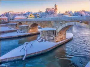 Ośnieżone przęsła kamiennego mostu na Dunaju w Regensburgu