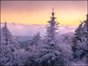 Zachód słońca w zamglonych górach zimową porą