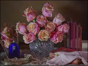 Bukiet róż obok lusterka perfum i pereł
