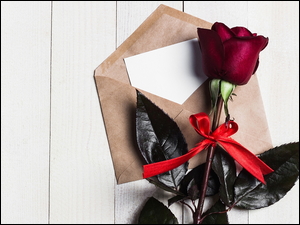 Czerwona róża na brązowej kopercie z kartką