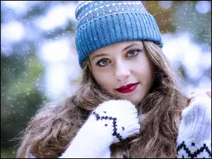 Dziewczyna w zimowej czapce i dłonie otulone rękawami