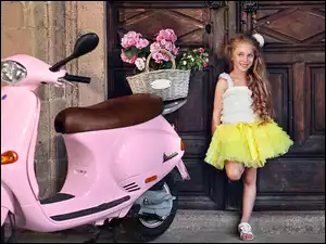 Uśmiechnięta dziewczynka obok motocykla Vespa