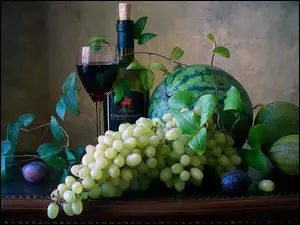 Arbuz i winogrona obok butelki wina na stole