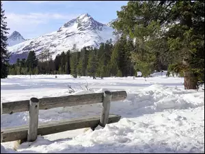 Widok z ławki w śniegu na ośnieżone góry