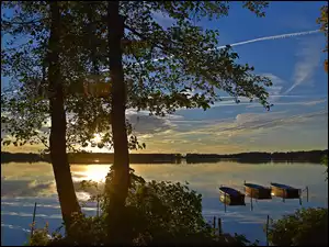 Trzy łódki na jeziorze o zachodzie słońca