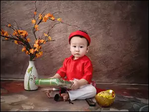Mały wietnamski chłopiec z prezentem obok kwiatów w wazonie