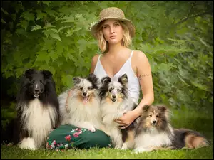 Kobieta w kapeluszu z gromadką psów w parku