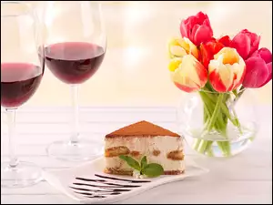 Kawałek ciasta obok tulipanów w wazonie