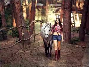 Kobieta spacerująca z koniem po lesie