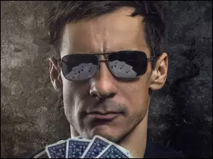 Mężczyzna w ciemnych okularach z kartami
