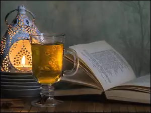 Szklanka herbaty przy lampionie i książce