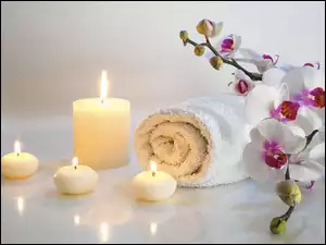 Dekoracja ze świecami, ręcznikiem i kwiatami w SPA