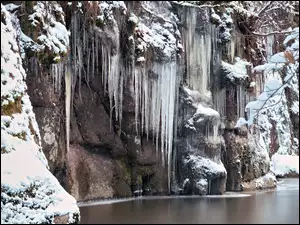 Śnieg i sople na skalnym wodospadzie