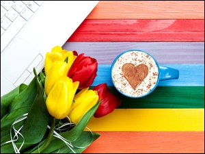 Kawa w filiżance obok tulipanów i laptopa