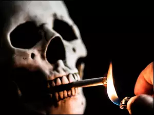 Dłoń odpalająca papierosa w czaszce