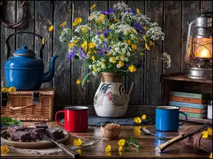 Niebieski czajnik obok kwiatów w wazonie