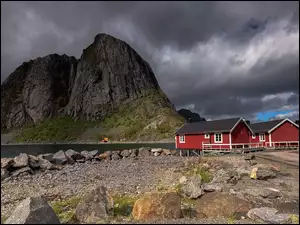 Czerwone domy i góry na norweskich Lofotach pod ciemnymi chmurami