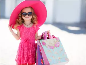 Dziewczynka w okularach i różowym kapeluszu z zakupami