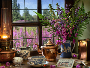 kwiaty w dzbanku obok lampy naftowej i bibelotów na stole przy oknie
