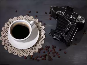 Filiżanka kawy z ziarnami i aparatem fotograficznym