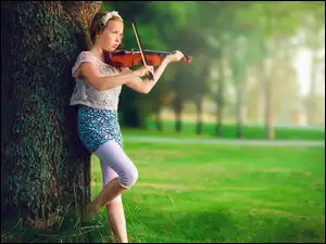 Dziewczynka obok drzewa z skrzypcami
