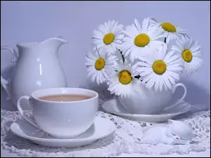 Herbatka w białej porcelanie z bukietem rumianków