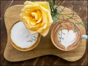 Widok z góry na cappuccino w filiżankach i żółtą różę
