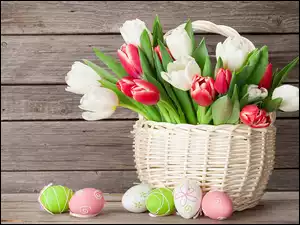 Kolorowe tulipany w białym koszyku obok pisanek