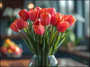 Czerwone tulipany w szklanym wazonie na rozmazanym tle