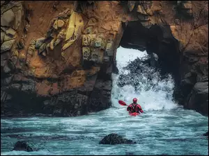 Kajakarz przepływajacy przez skały