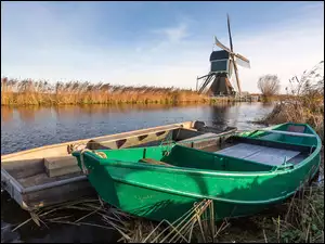 Łodzie przy brzegu rzeki w Holandii i wiatrak w tle