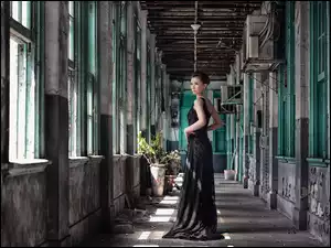 Azjatka w długiej czarnej sukni pozuje w zaniedbanym wnętrzu