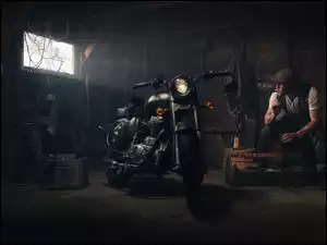 Siedzący mężczyzna i motocykl w warsztacie