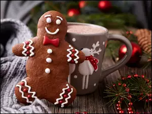 Pierniczek i kubek kakao obok świątecznych dekoracji