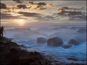 Fotograf na skałach i wzburzone morze wśród kamieni