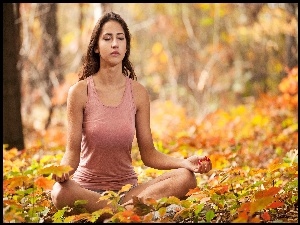 Medytująca kobieta na jesiennych liściach w lesie