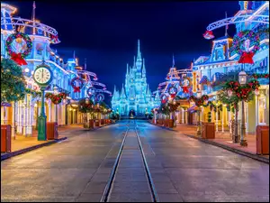 Ulice miasta świątecznie przystrojone i oświetlony Disneyland w tle