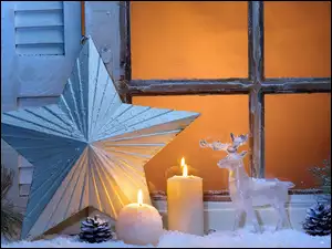 Parapet okna świątecznie ozdobiony w blasku świec