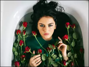 Brunetka w wannie z wodą i czerwonymi różami