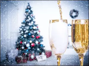 Kieliszki szampana na Nowy Rok z choinką w tle