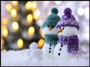 Bałwanki w czapeczkach na śniegu w blasku światełek choinkowych